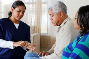 caregiver giving medicines to an old couple