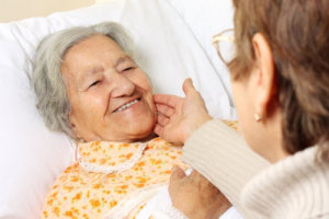 old woman in bed assisted by her caregiver
