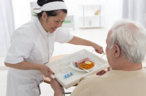 caregiver serving food to an old man